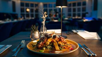 A dining table with a plate of food, cutlery, and a lamp.