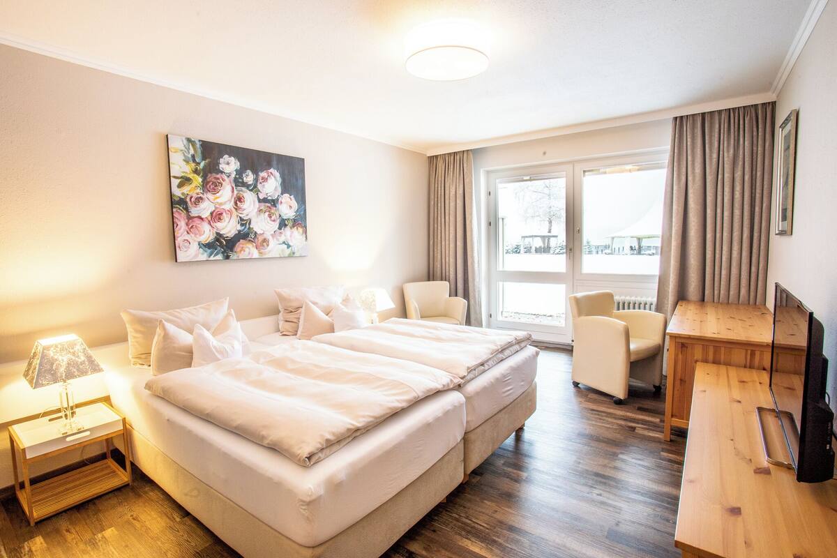Une chambre d’hôtel avec un grand lit, un bureau, une chaise et un tableau au mur.