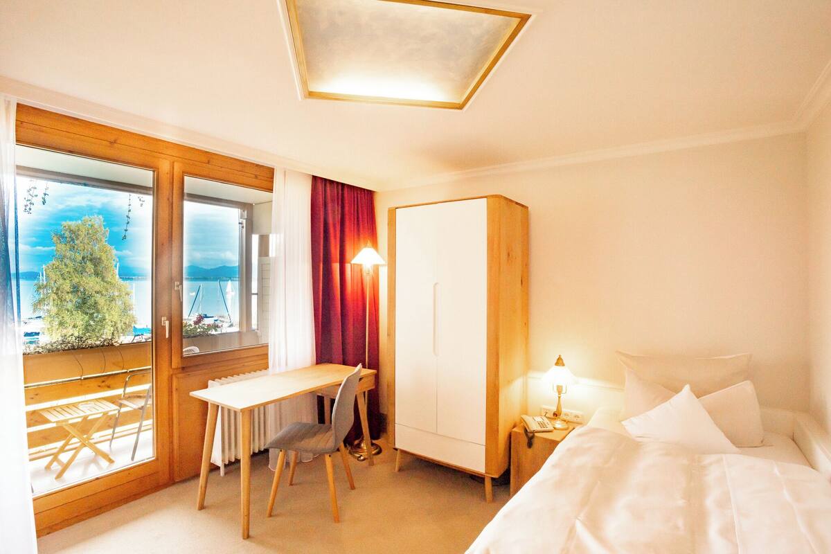 Une chambre d’hôtel équipée d’un lit, d’un bureau, d’une chaise, d’une armoire et offrant une vue sur l’extérieur.