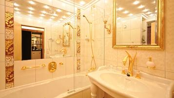 A luxurious bathroom with a large bathtub, a sink with gold fixtures, and a mirror with a gold frame.