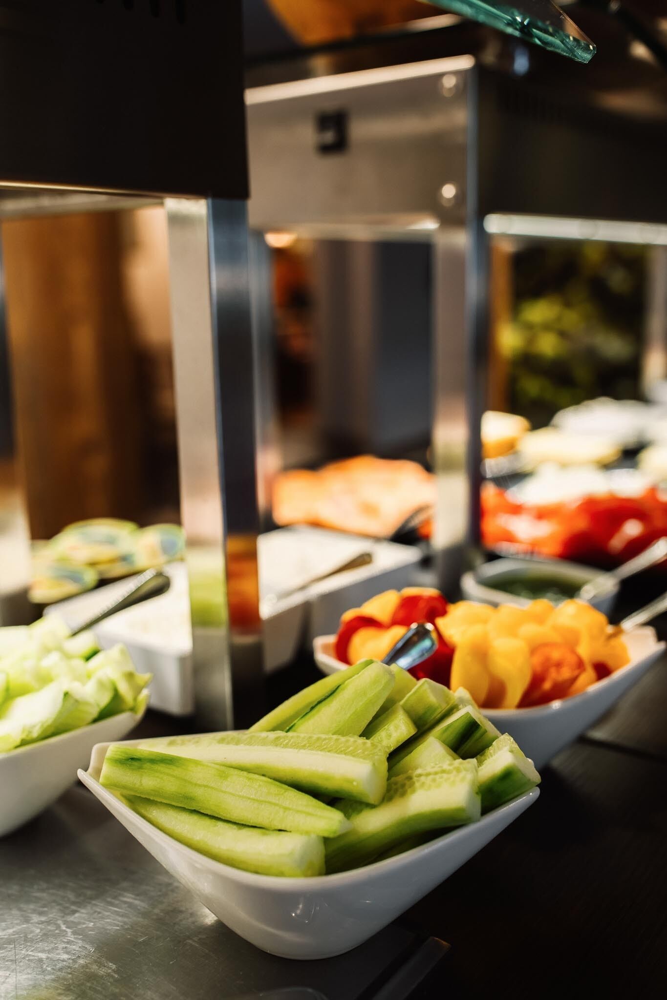 Un bufé con diversos alimentos, incluyendo pepinos en rodajas y otras verduras.