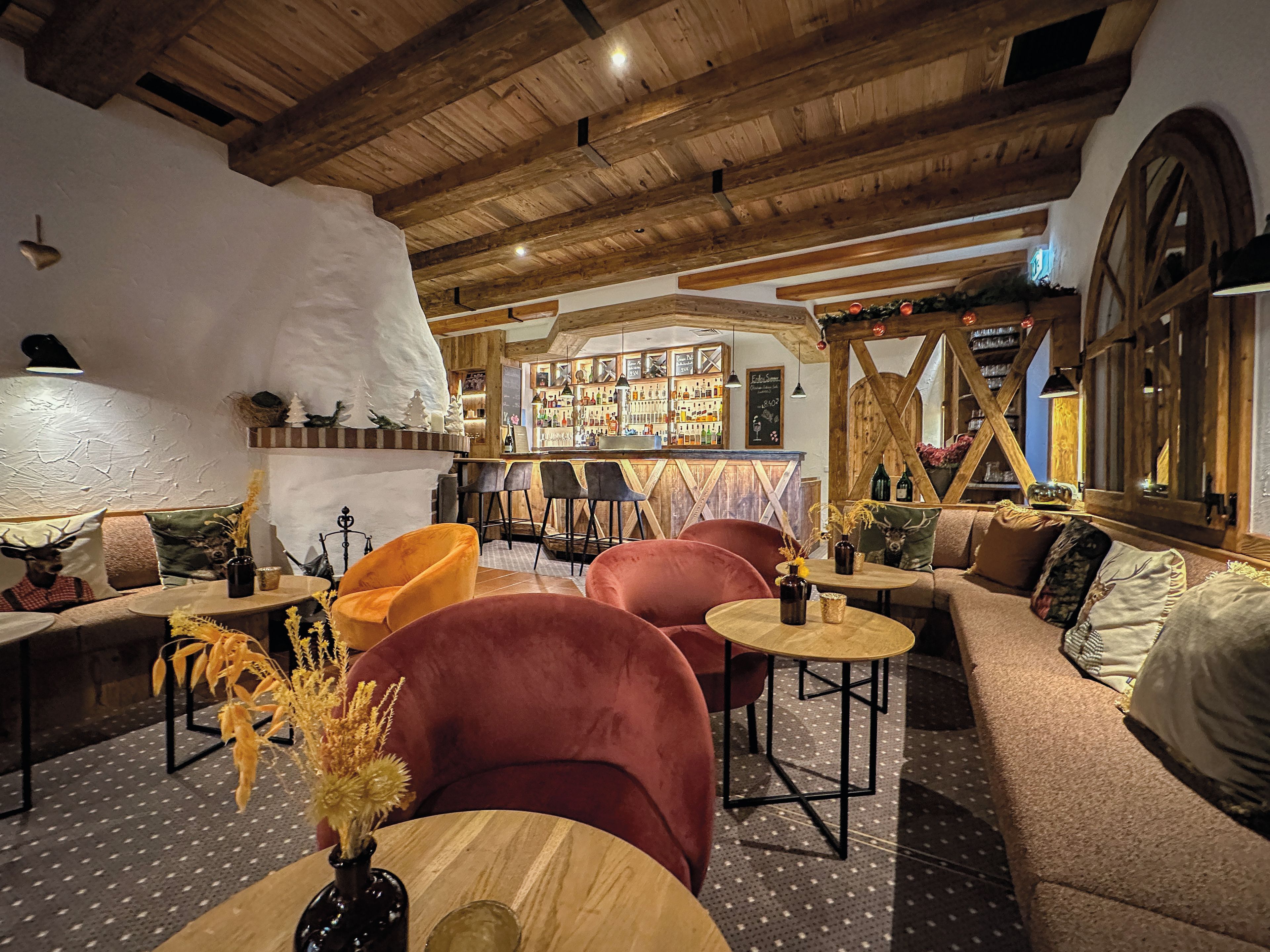 A cozy interior with wooden beams, a bar area, and seating arrangements.