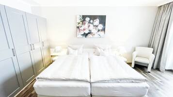 Ein Hotelzimmer mit einem großen Bett, einem Sessel, einem Kleiderschrank und einem Bild an der Wand.