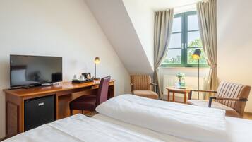Een hotelkamer met een bed, bureau, televisie en een raam met gordijnen.
