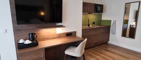 A modern kitchen with a built-in TV, wooden cabinets, and a dining area with a chair.