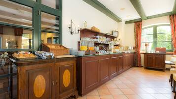 Una barra de desayuno alargada con un mueble de madera, una ventana con cortinas y una estantería con frascos de vidrio.