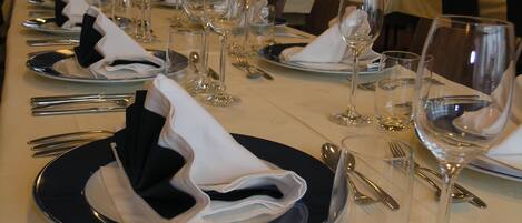 A long dining table set with multiple place settings, including plates, cutlery, and wine glasses.