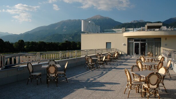 Une terrasse extérieure avec des tables et des chaises, offrant une vue sur un paysage montagneux.
