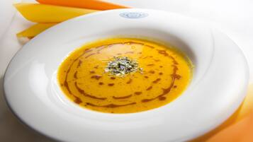 Un plato blanco con un bol de sopa y una guarnición.