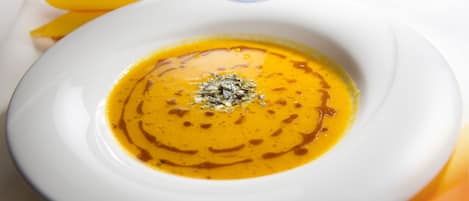 A bowl of soup with a garnish on a white plate.