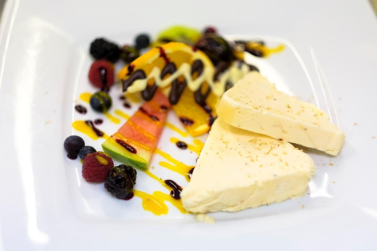 Ein weißer Teller mit einem Dessert aus Fruchtscheiben und einer gelben Soße.
