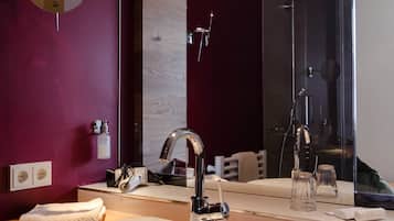 A modern bathroom with a white sink, a large mirror, and a wooden ceiling.