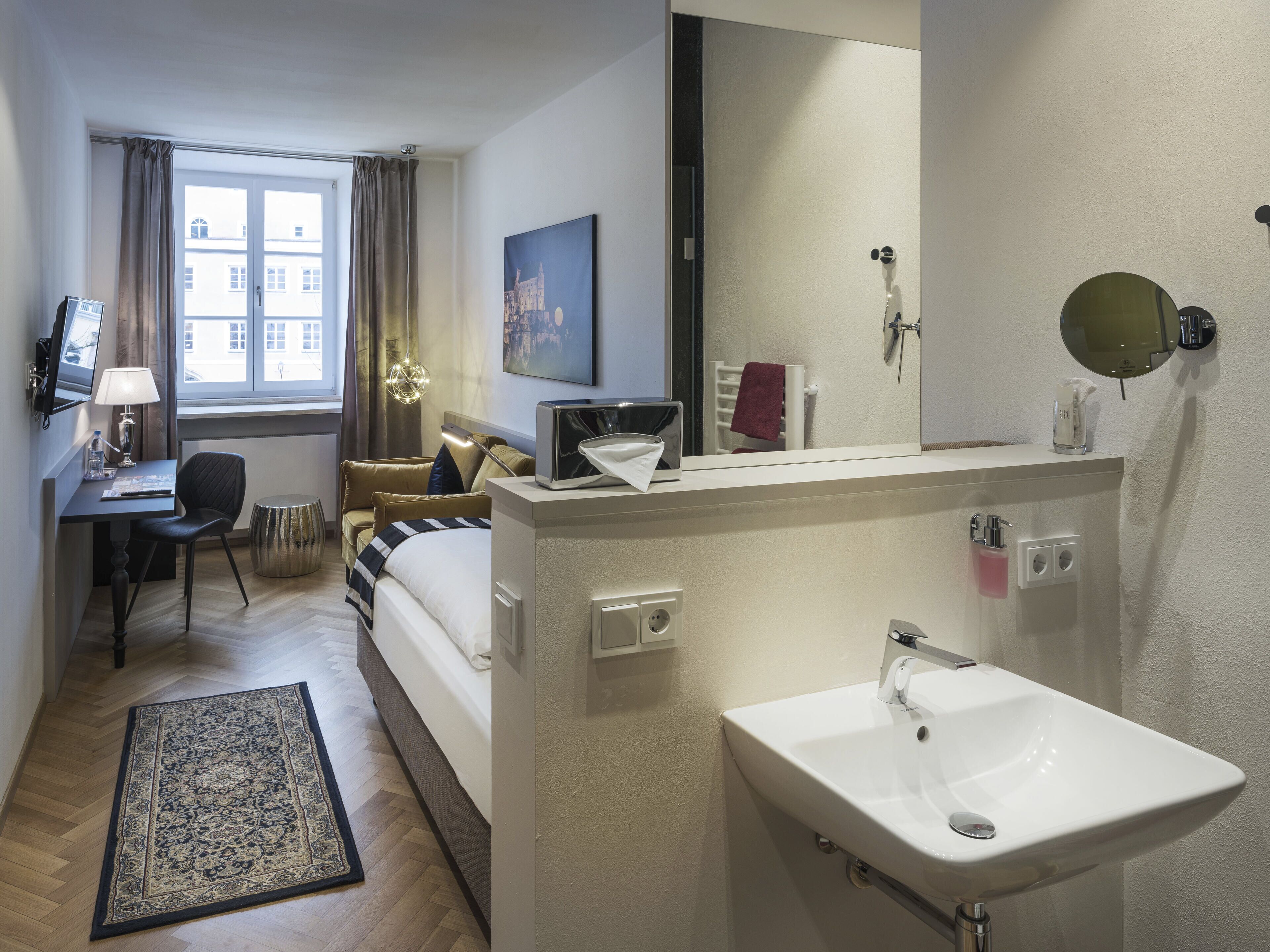 Habitación de hotel con cama, escritorio, silla y un espejo grande.