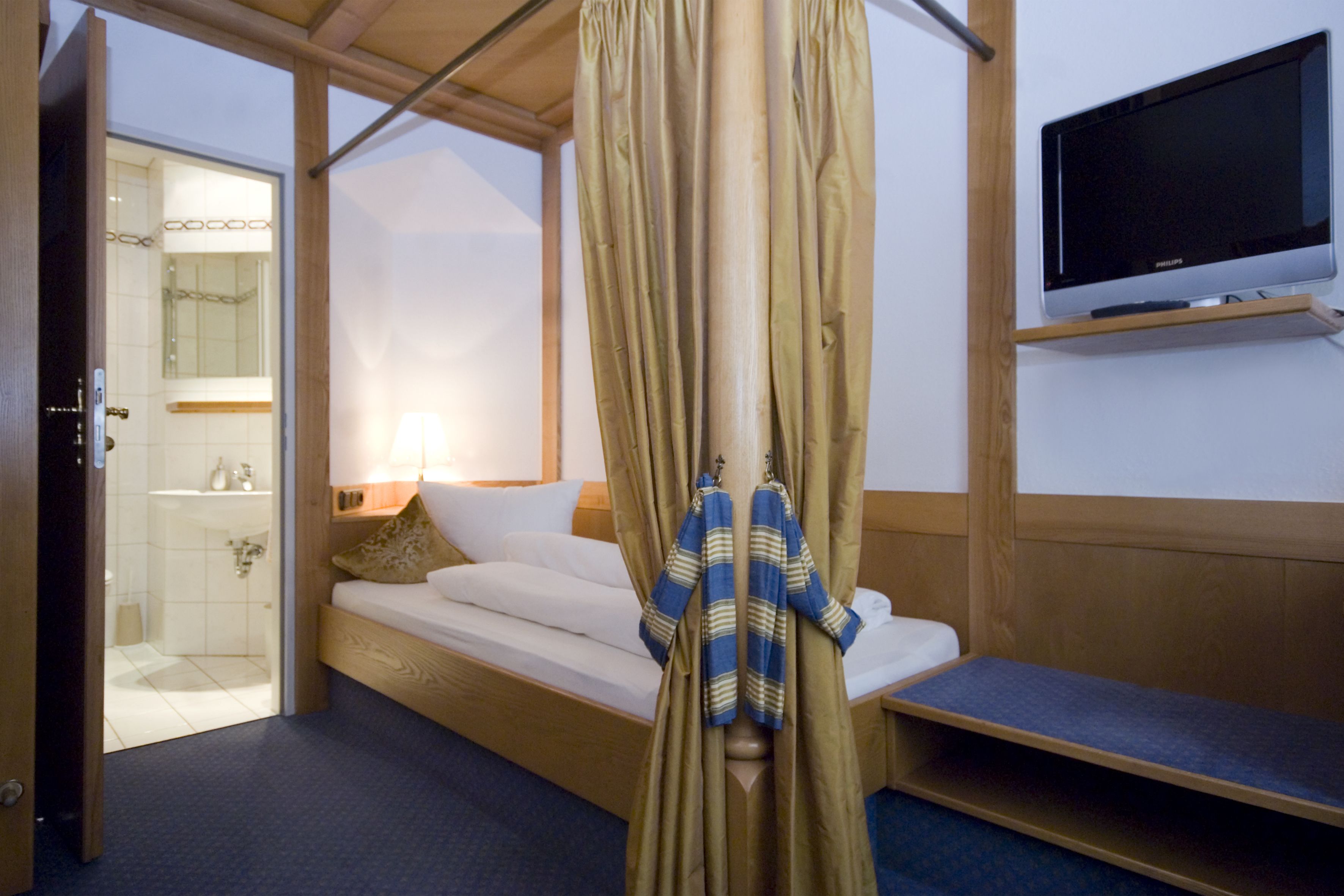 A room with a bed, a TV, and a curtain.