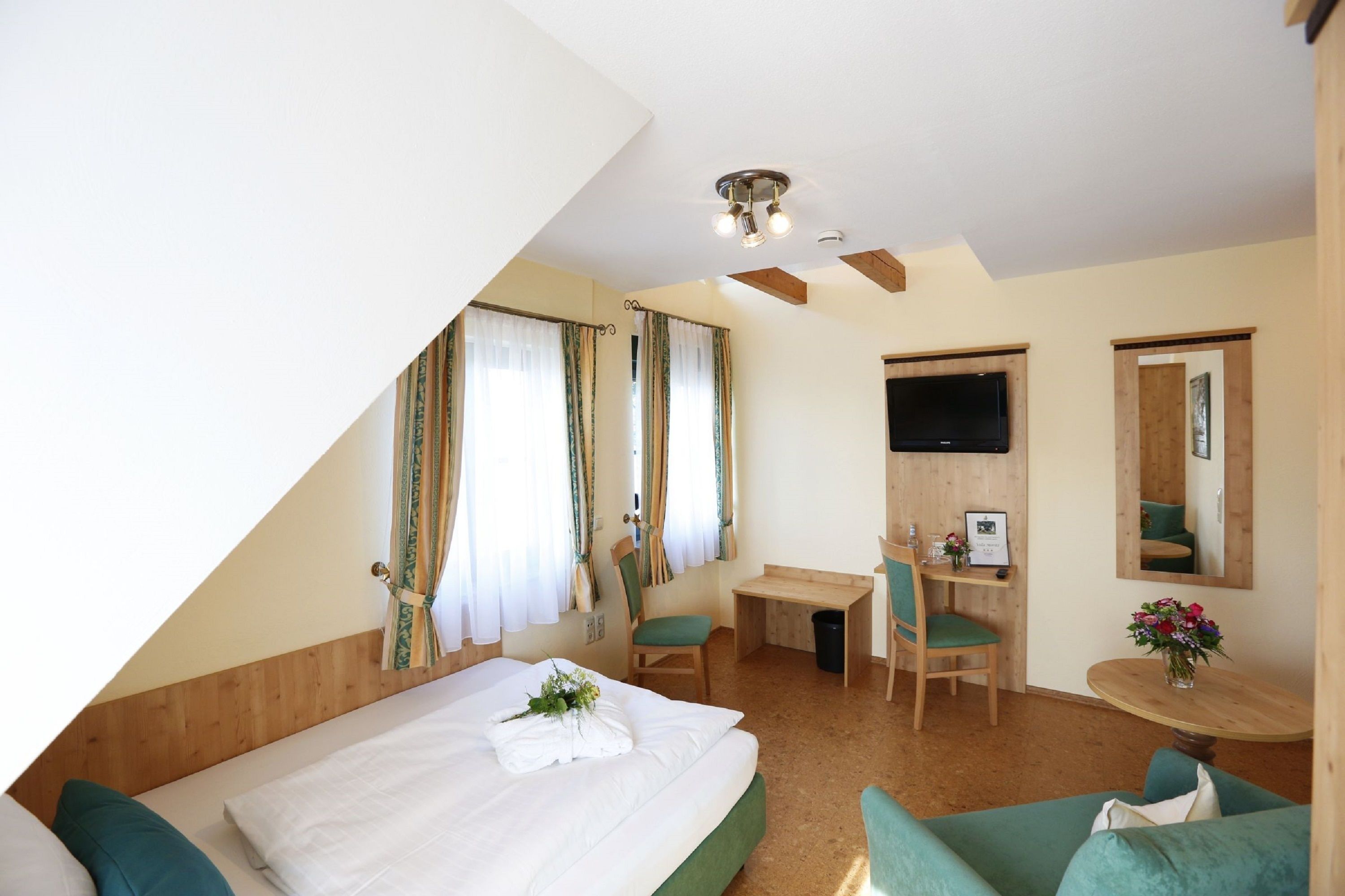 Une chambre d’hôtel avec un lit, un bureau, une chaise, une petite table et un téléviseur.