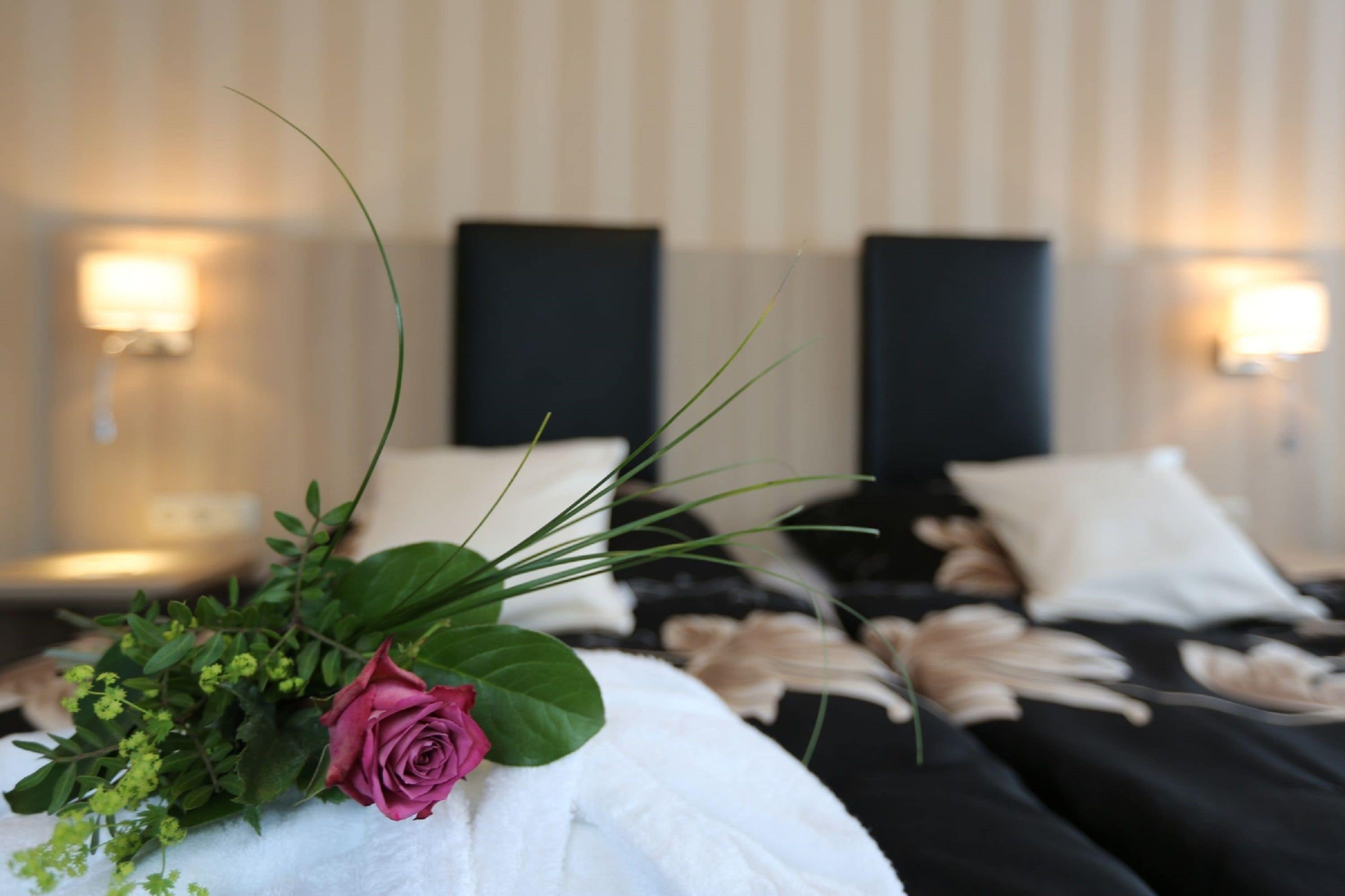 Een hotelkamer met een net opgemaakt bed, een nachtkastje en een wandlamp.