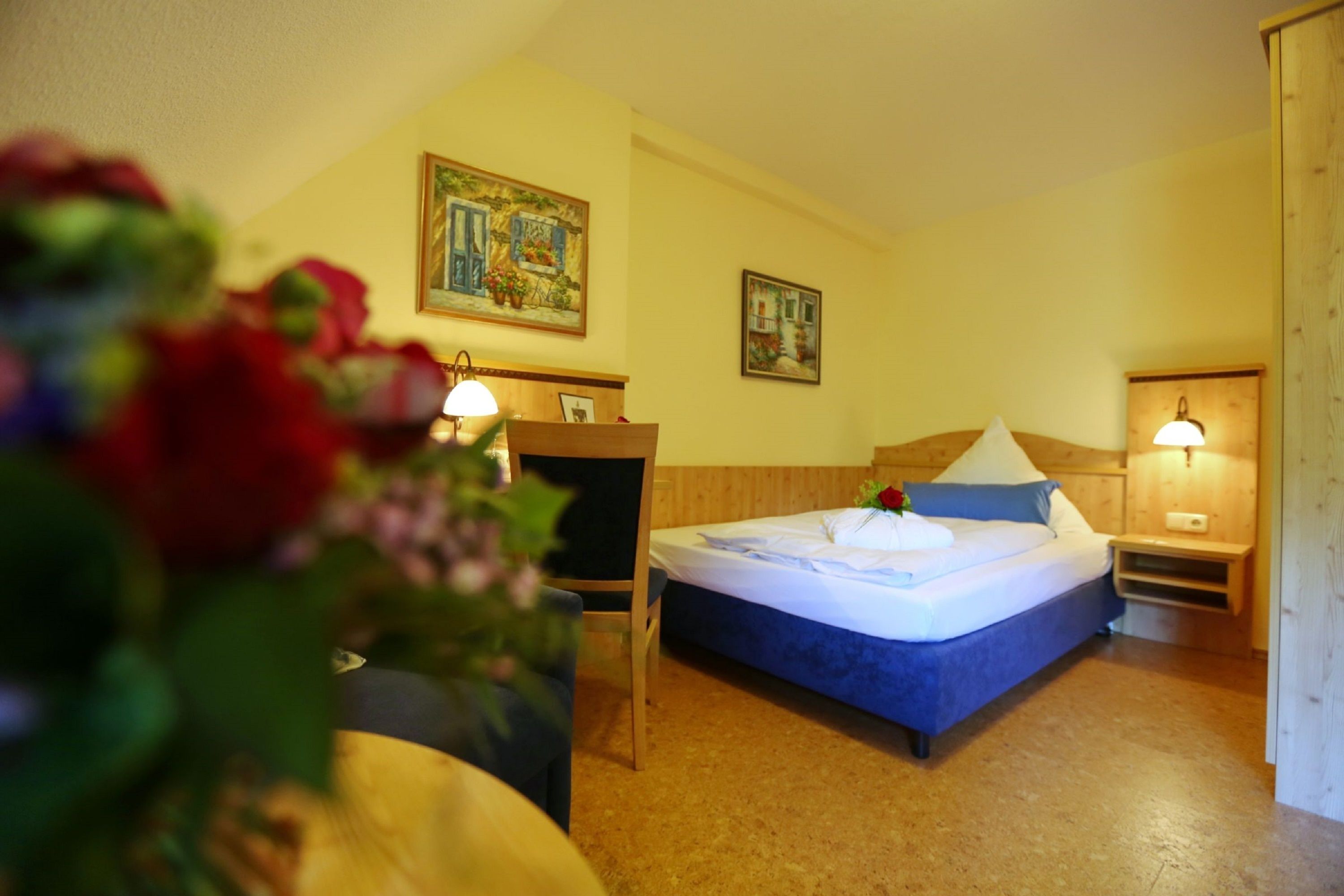 Una habitación de hotel con una cama, dos lámparas de pared, un cabecero de madera y dos cuadros.