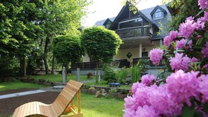 Una silla de jardín de madera con una casa al fondo.