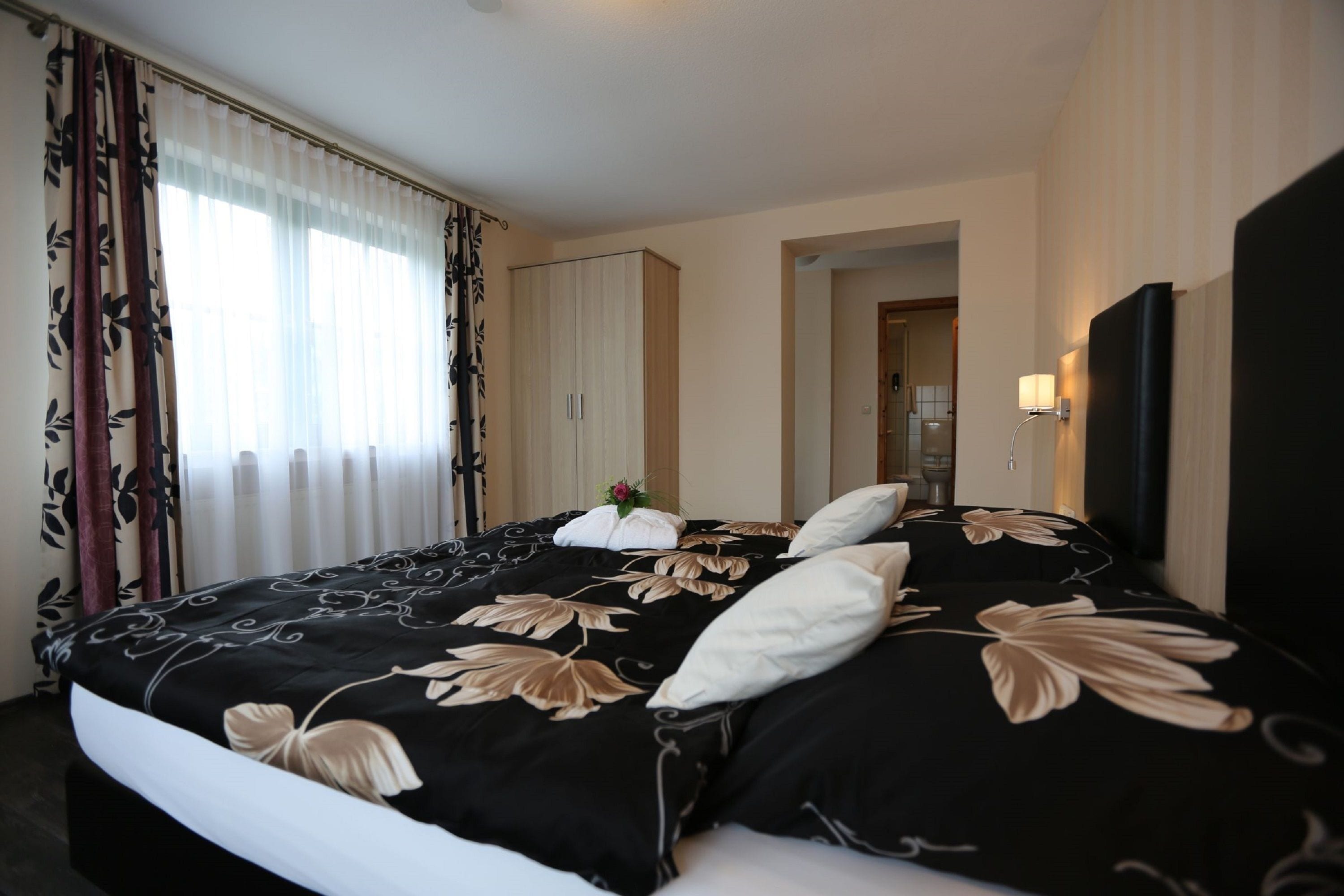 A hotel room with a large bed, a wardrobe, a mirror, and a wall-mounted TV.