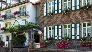 A hotel with a sign indicating it is a restaurant, multiple balconies with flower boxes, and a brick facade. - Hotel Restaurant Pollmanns (Ernst)