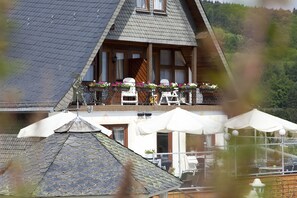 Situated in a serene valley, this chalet-style building offers a balcony with outdoor seating and flower boxes.