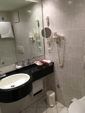 A modern bathroom with a large sink, a mirror, a hairdryer, and a toilet. - Hotel Restaurant Zum Felsenkeller (Sohren)