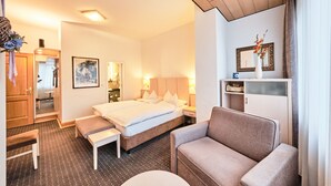 Una habitación de hotel con una cama, un sofá, un banco, un escritorio y un espejo.