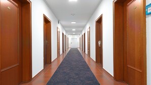 Un long couloir bordé de portes en bois de chaque côté et recouvert d’un tapis bleu.