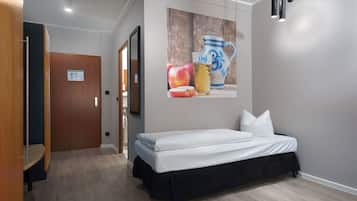 Ein Hotelzimmer mit einem Bett, einer Holztür, einem Wandbild und einer Leuchte.