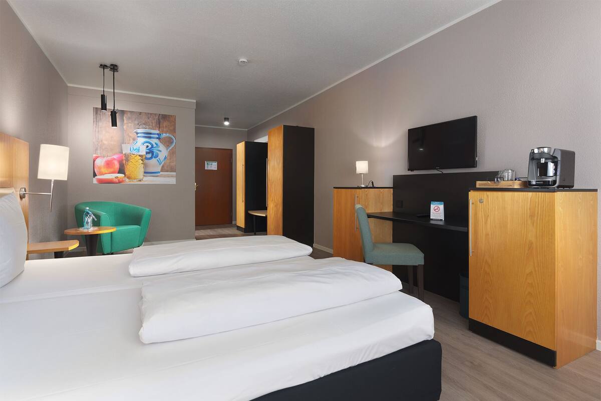Une chambre d’hôtel équipée d’un lit, d’un bureau, d’une chaise, d’une télévision et d’une machine à café.