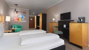 Een hotelkamer met een bed, bureau, stoel, televisie en koffieapparaat.