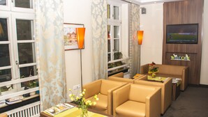 Habitación de hotel con zona de estar, televisión y ventana con cortinas.