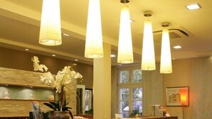 Un área de recepción con mostrador verde, iluminación en el techo y un ventanal con luz natural.