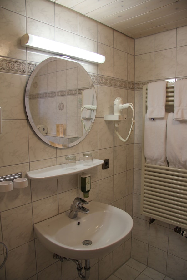 Une salle de bain équipée d’un lavabo, d’un miroir, d’un porte-serviettes et d’un radiateur.