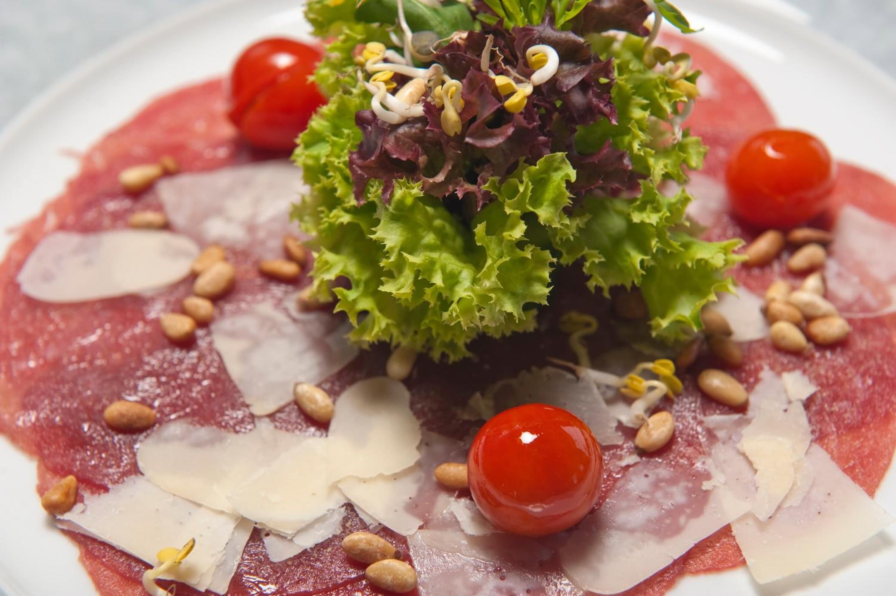 Un plato de comida con ensalada, tomates cherry y queso.