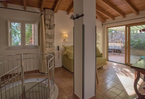 A room with a spiral staircase, a stone wall, a bed, a table, and a patio area with a table and chairs. - Hotel Villa Schuler (Taormina)