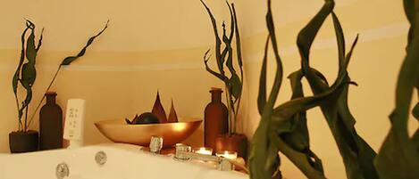 A bathroom with a bathtub, a bowl, and several potted plants.