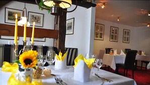 A dining table set with candles, sunflowers, and napkins. - Hotel Faldernpoort (Emden)