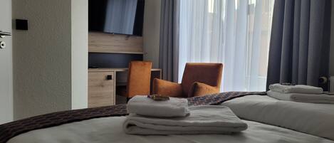 Una habitación de hotel con cama, escritorio, silla y televisión.