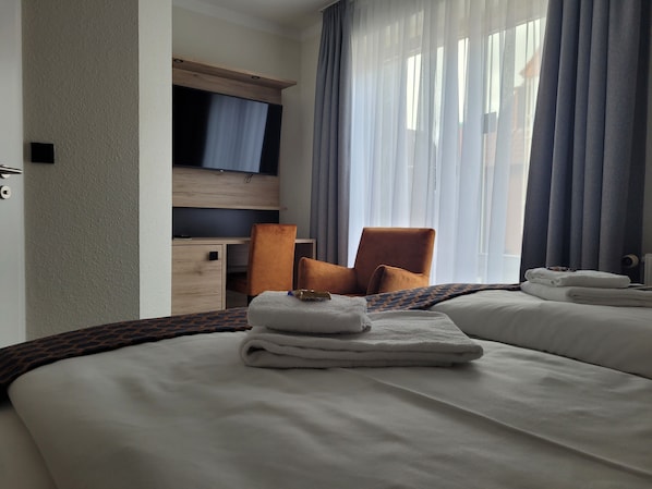 Una habitación de hotel con cama, escritorio, silla y televisión.
