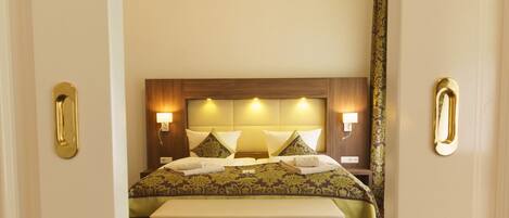 A hotel room with a large bed, two bedside lamps, and a headboard with built-in lighting.