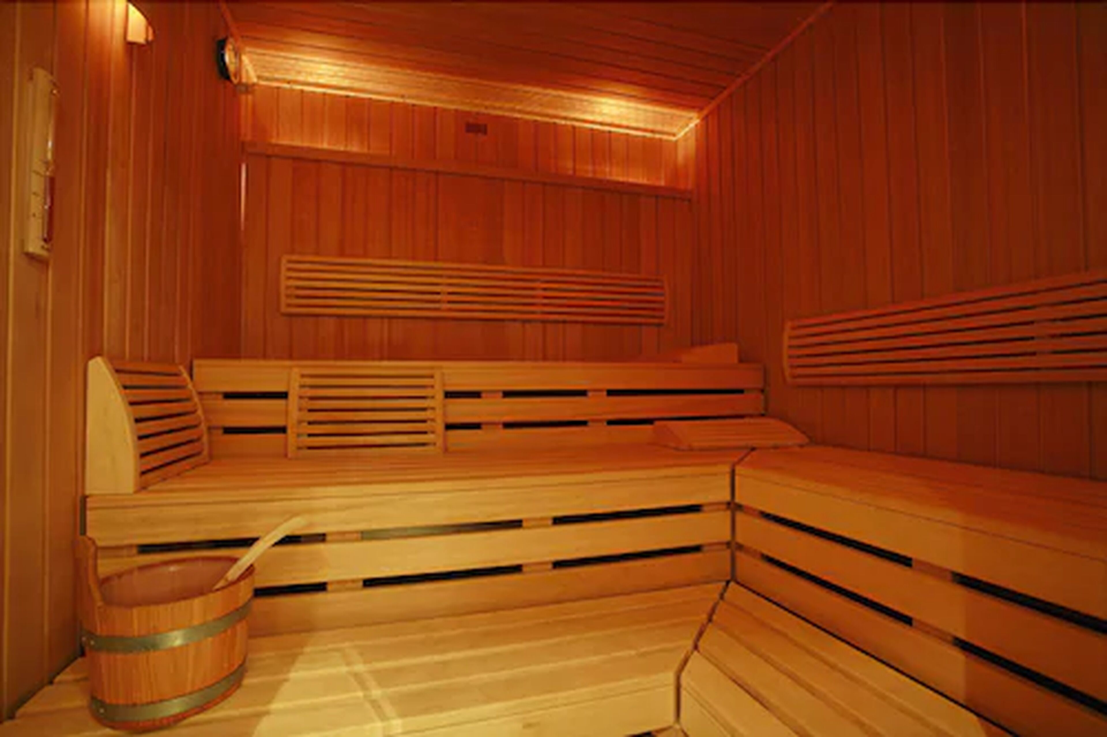 A sauna with wooden benches and a wooden bucket.
