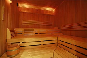 A sauna with wooden benches and a wooden bucket.