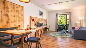 A cozy living room with a sofa, a dining area with a table and chairs, and a TV.