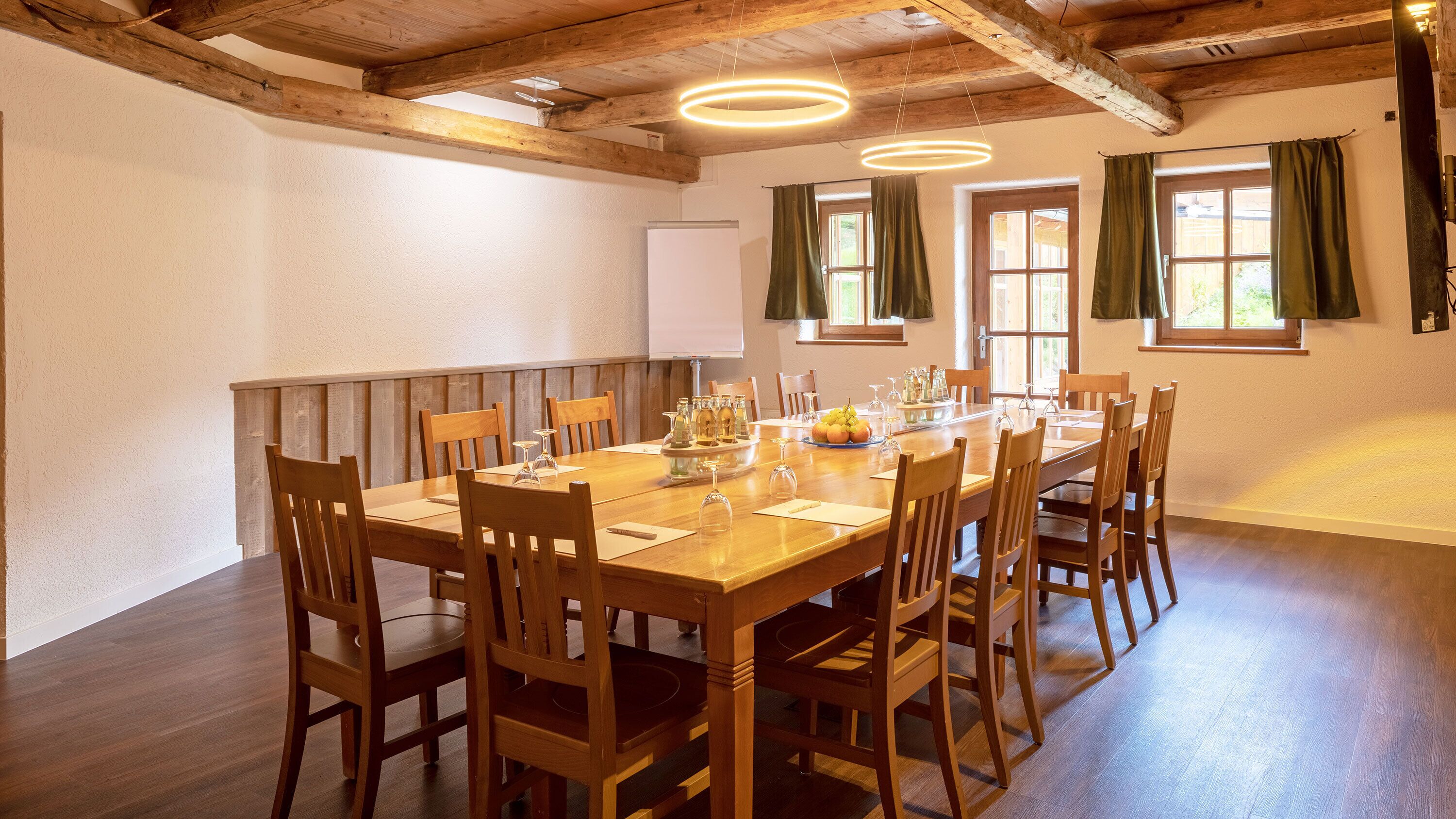Comedor con una mesa de madera dispuesta para ocho personas, rodeado de sillas.