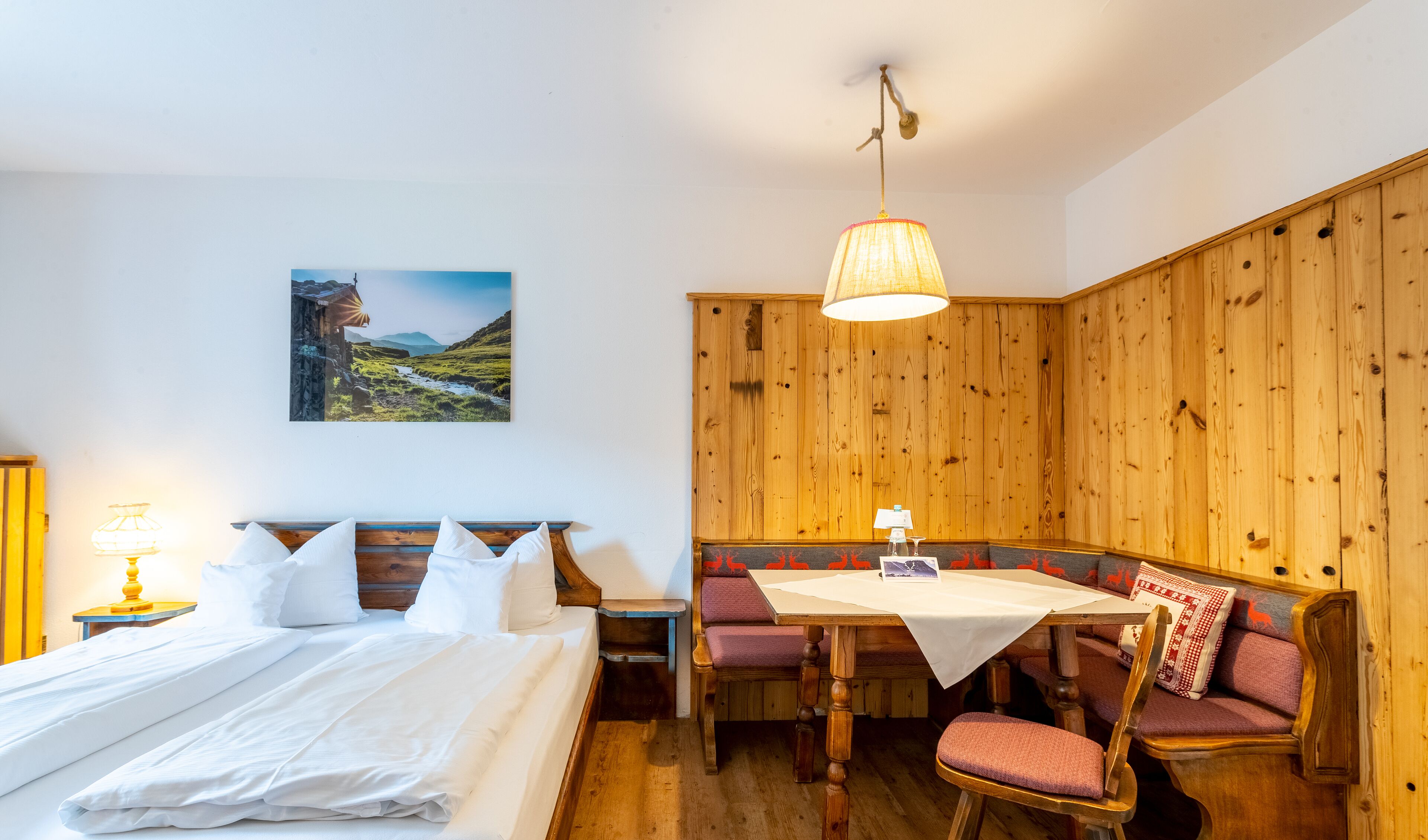 Una habitación con una cama, una mesa y un banco.