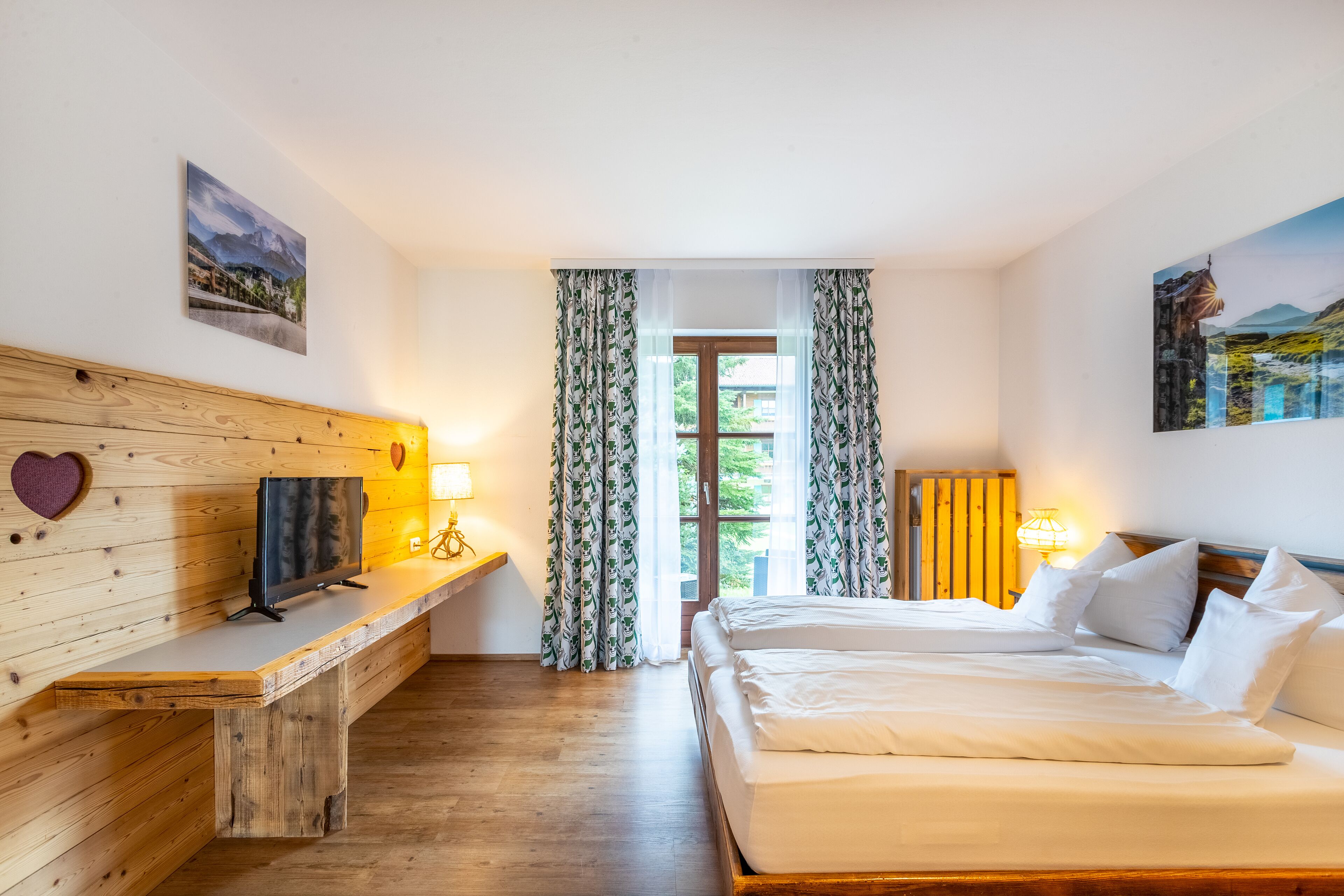Une chambre à coucher avec une tête de lit en bois, un lit recouvert de draps blancs, une table de chevet avec une lampe et une fenêtre avec des rideaux.