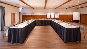 Un salón de conferencias con una larga mesa, sillas y una pizarra.