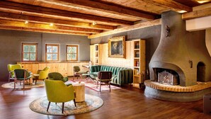Ein gemütliches Wohnzimmer mit Holzbalken, Kamin und einem grünen Sofa.