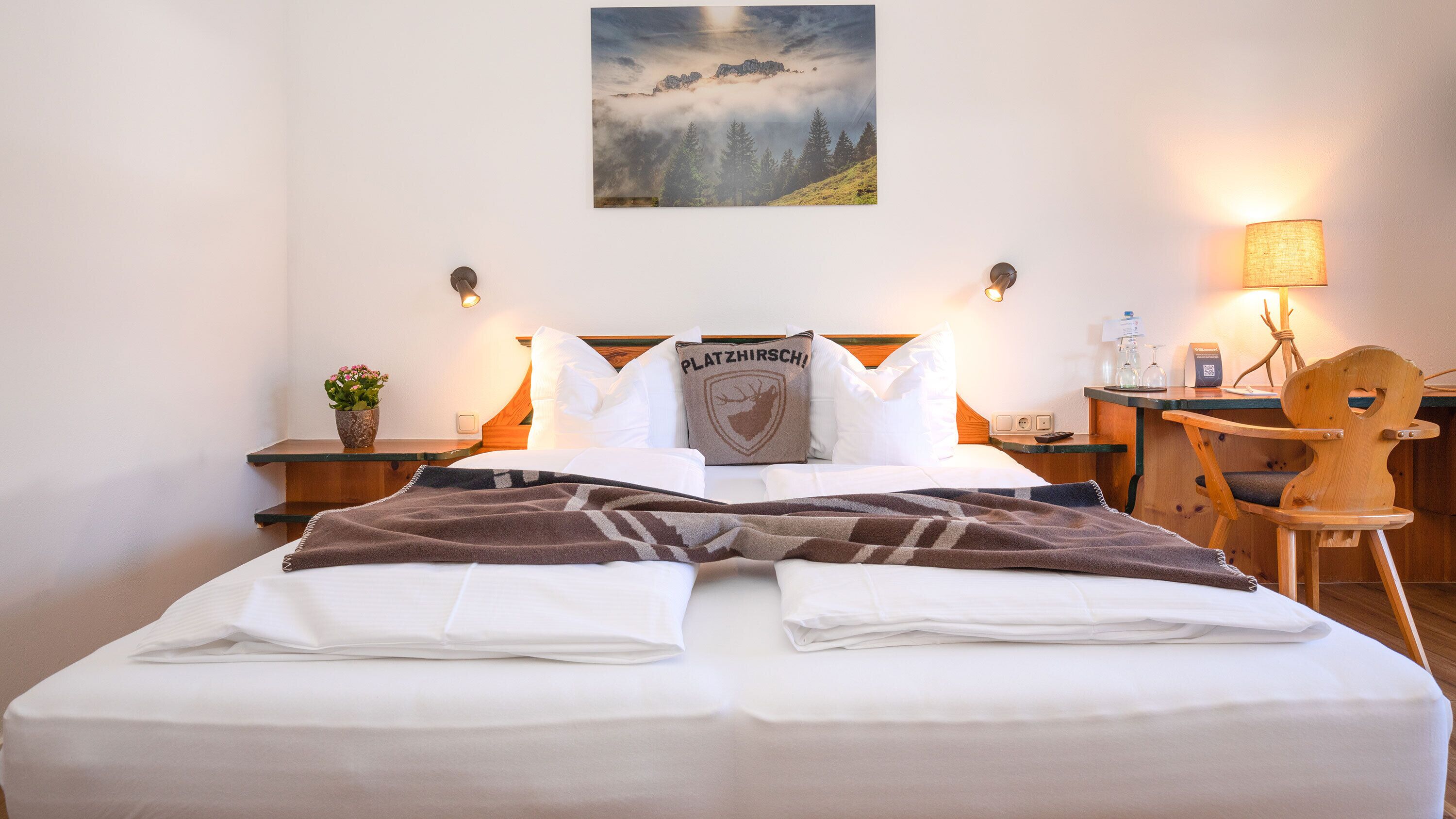 Ein Hotelzimmer mit Bett, Schreibtisch, Stuhl, Lampe und einem Bild an der Wand.